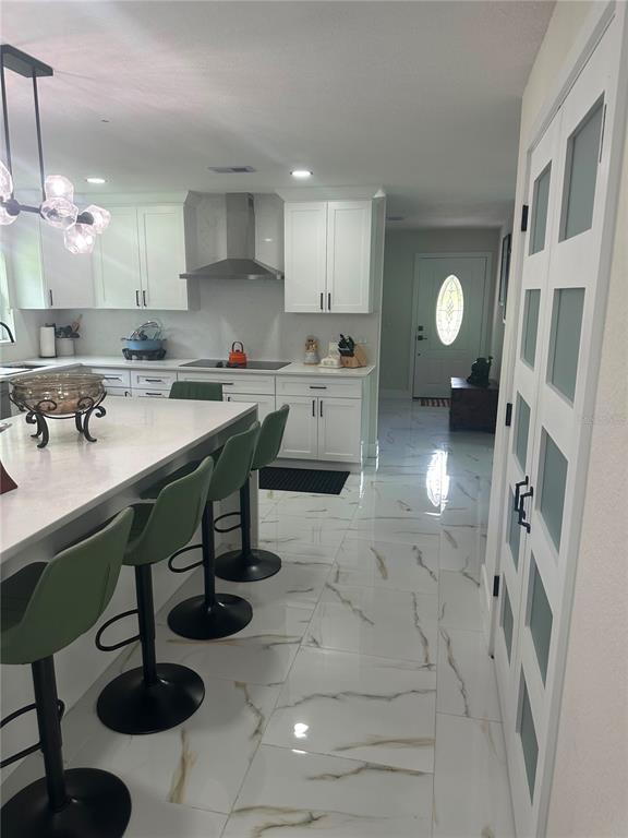 A kitchen with white cabinets, a large island with green stools, and marble-look tile flooring — 7251 NE 227TH PLACE, CITRA, FL