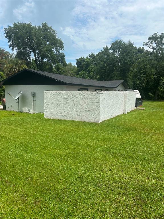 A white stucco house with a dark roof and a low privacy wall in the yard — 7251 NE 227TH PLACE, CITRA, FL