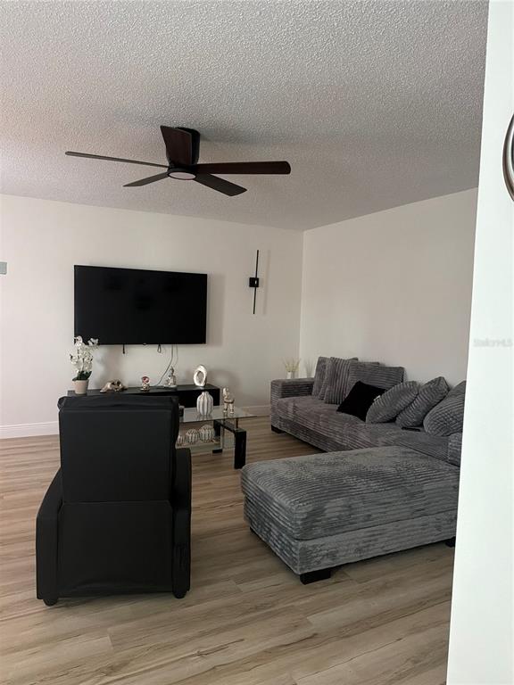 A living room features a gray sectional sofa, a black recliner, and a wall-mounted television — 9218 TUDOR DRIVE UNIT P101, TAMPA, FL