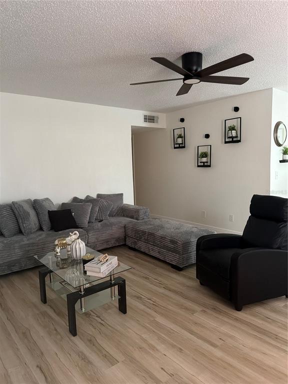 A living room features a grey sectional sofa, a black recliner, and a glass coffee table — 9218 TUDOR DRIVE UNIT P101, TAMPA, FL