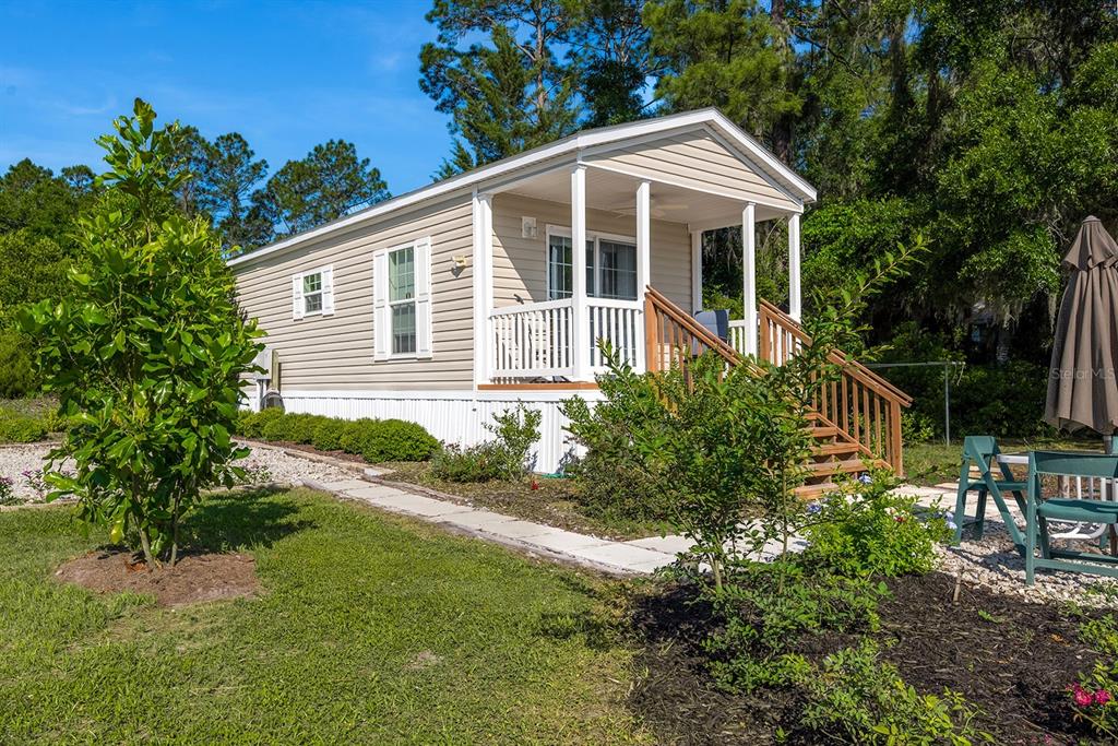 A tan mobile home with a front porch and wooden stairs sits on a grassy lot — 588 S COUNTY ROAD 21, HAWTHORNE, FL