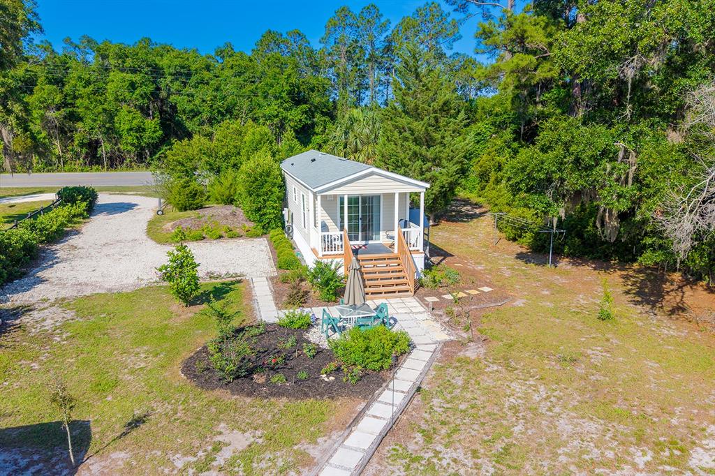 An aerial view shows a small house with a front porch, patio, and gravel driveway — 588 S COUNTY ROAD 21, HAWTHORNE, FL