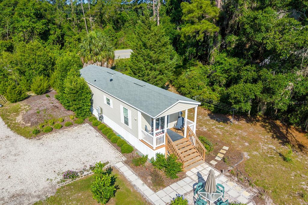 An aerial view of a single-wide mobile home with a front porch and gravel driveway — 588 S COUNTY ROAD 21, HAWTHORNE, FL