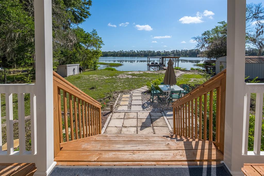 A wooden dock with a covered seating area extends into a calm lake — 588 S COUNTY ROAD 21, HAWTHORNE, FL
