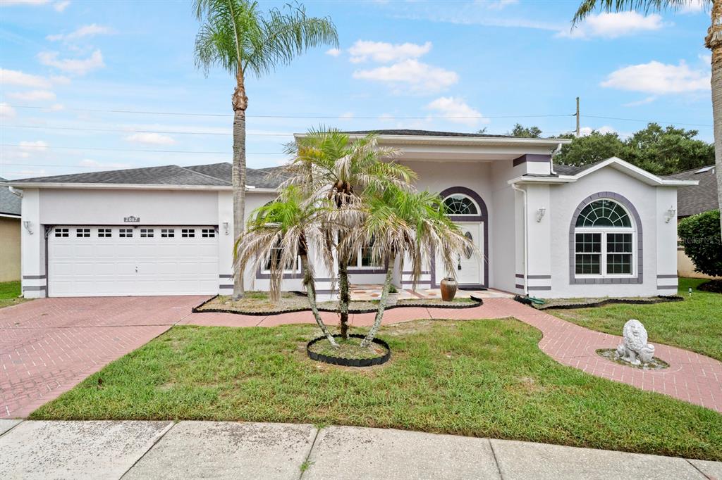A single-story house with a white stucco exterior, a two-car garage, and a palm tree — 2087 WESTBOURNE DRIVE, OVIEDO, FL