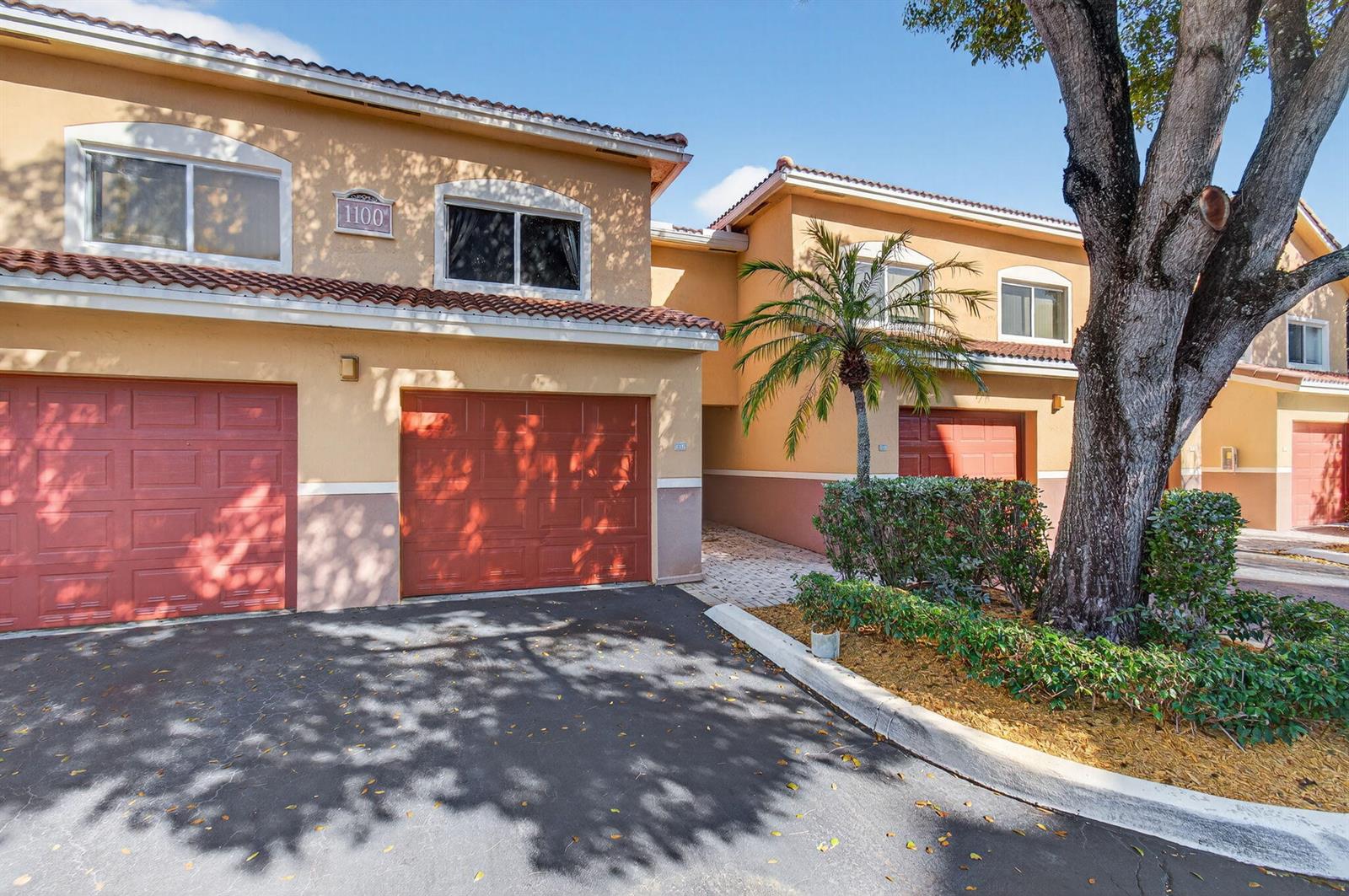 A two-story townhouse exterior features tan stucco walls, red tile roofs, and attached garages — 1100 Scotia Drive # 104, Hypoluxo FL 33462, HYPOLUXO, FL