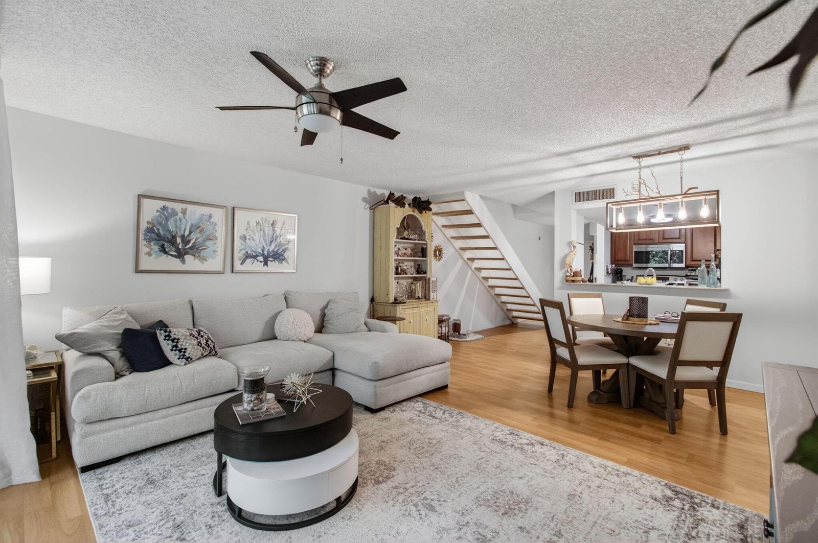 A living room with a sectional sofa, dining area, and stairs leading to an upper level — 1100 Scotia Drive # 104, Hypoluxo FL 33462, HYPOLUXO, FL