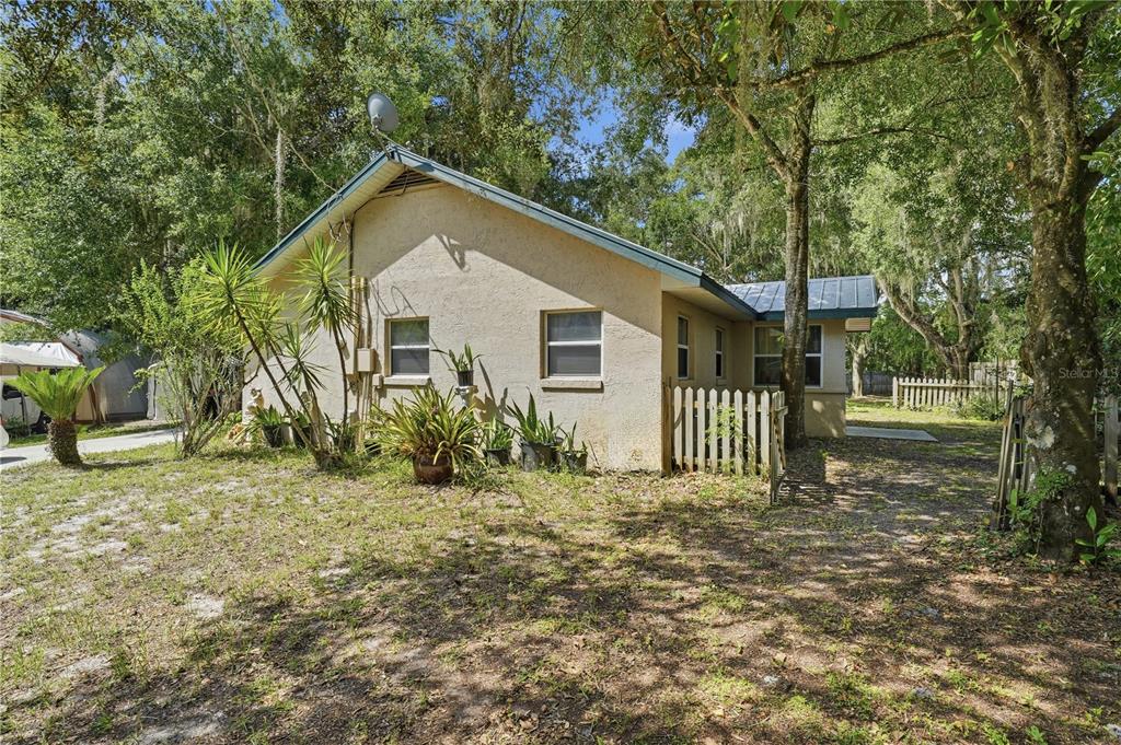 A single-story house with stucco siding and a metal roof sits on a wooded lot — 3543 N COUNTY ROAD 426, GENEVA, FL