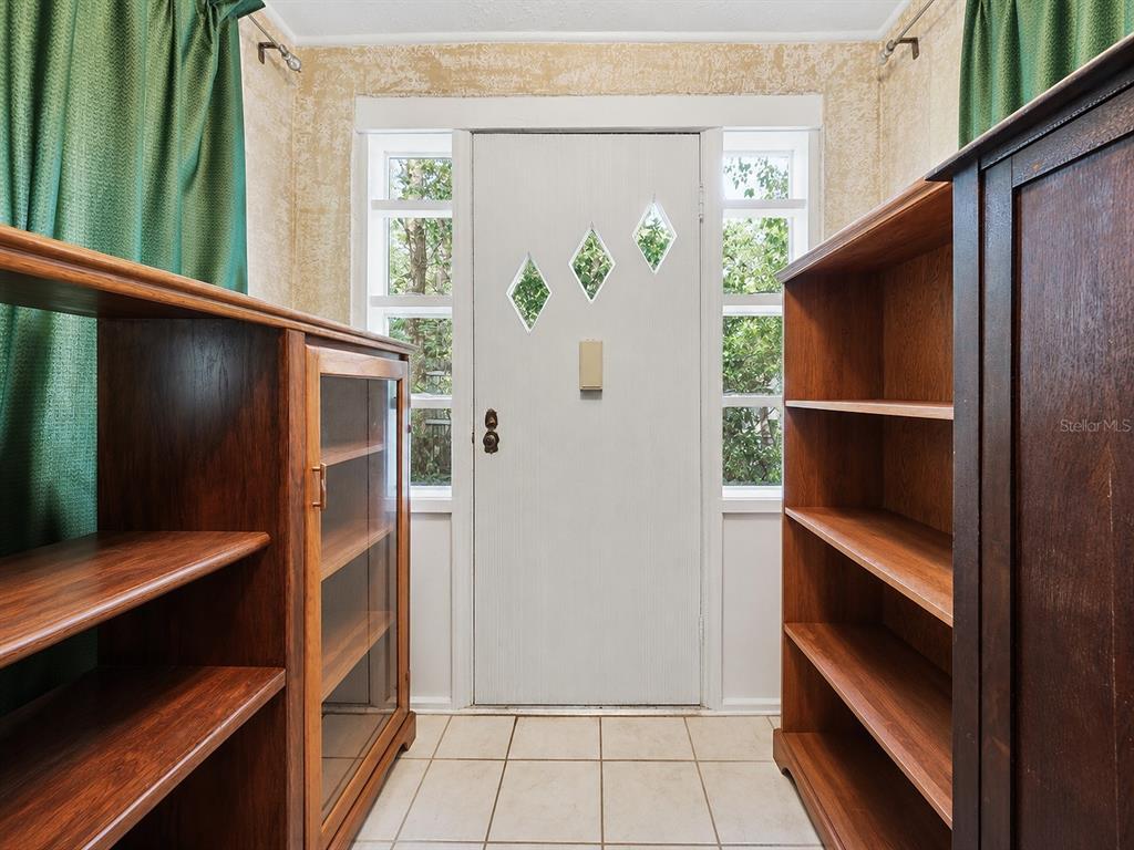 An entryway features a white door with diamond-shaped windows, tiled floors, and two wooden bookcases — 3543 N COUNTY ROAD 426, GENEVA, FL