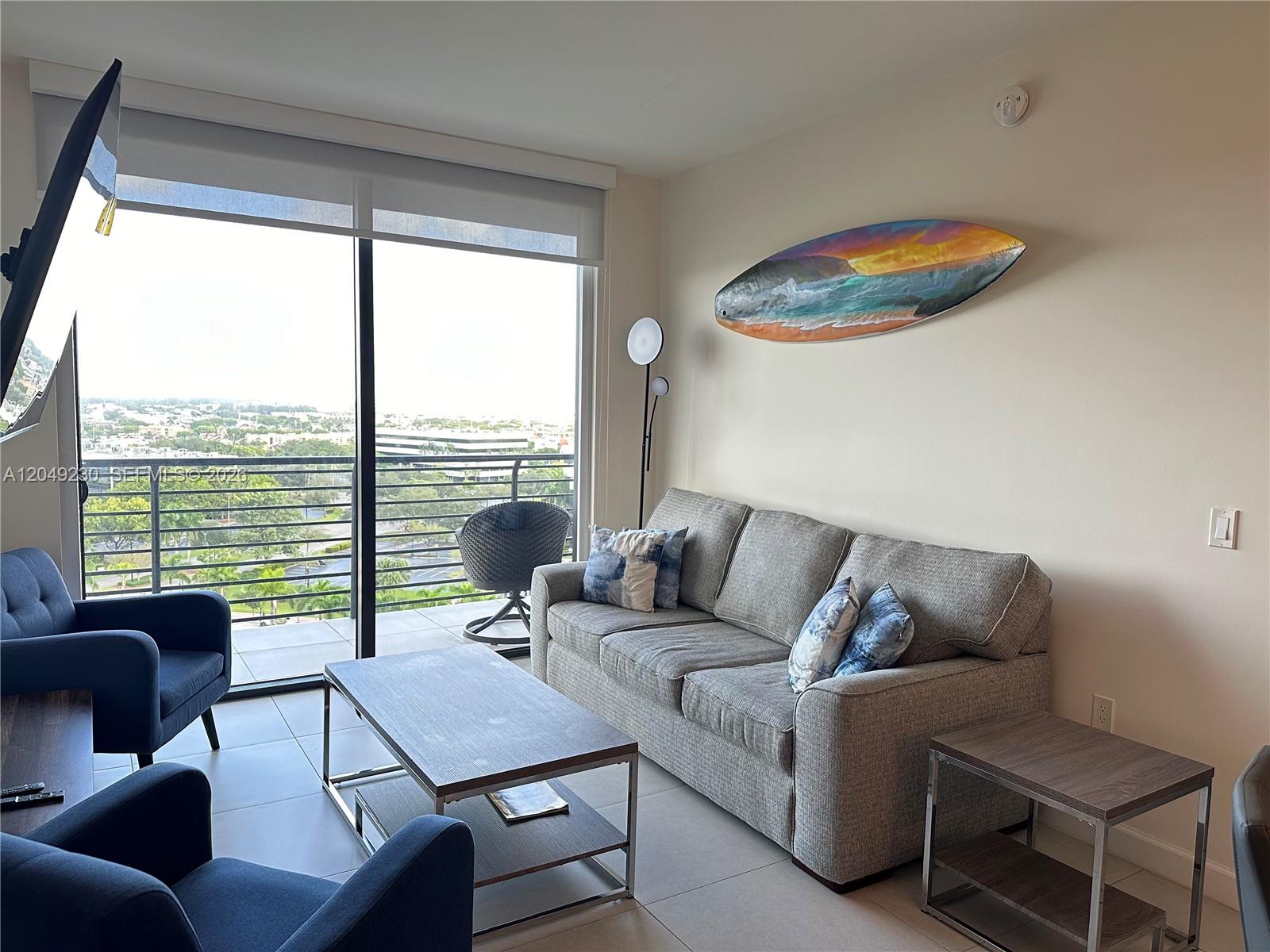 A living room features a gray sofa, blue armchairs, a coffee table, and a balcony view — 5350 NW 84th Ave # 1107, Doral FL 33166, DORAL, FL