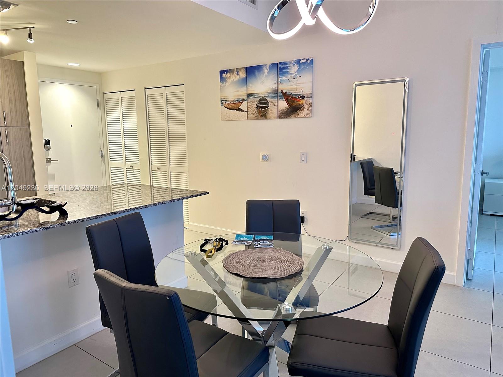 A dining area features a glass-topped table, four black chairs, and a wall-mounted mirror — 5350 NW 84th Ave # 1107, Doral FL 33166, DORAL, FL