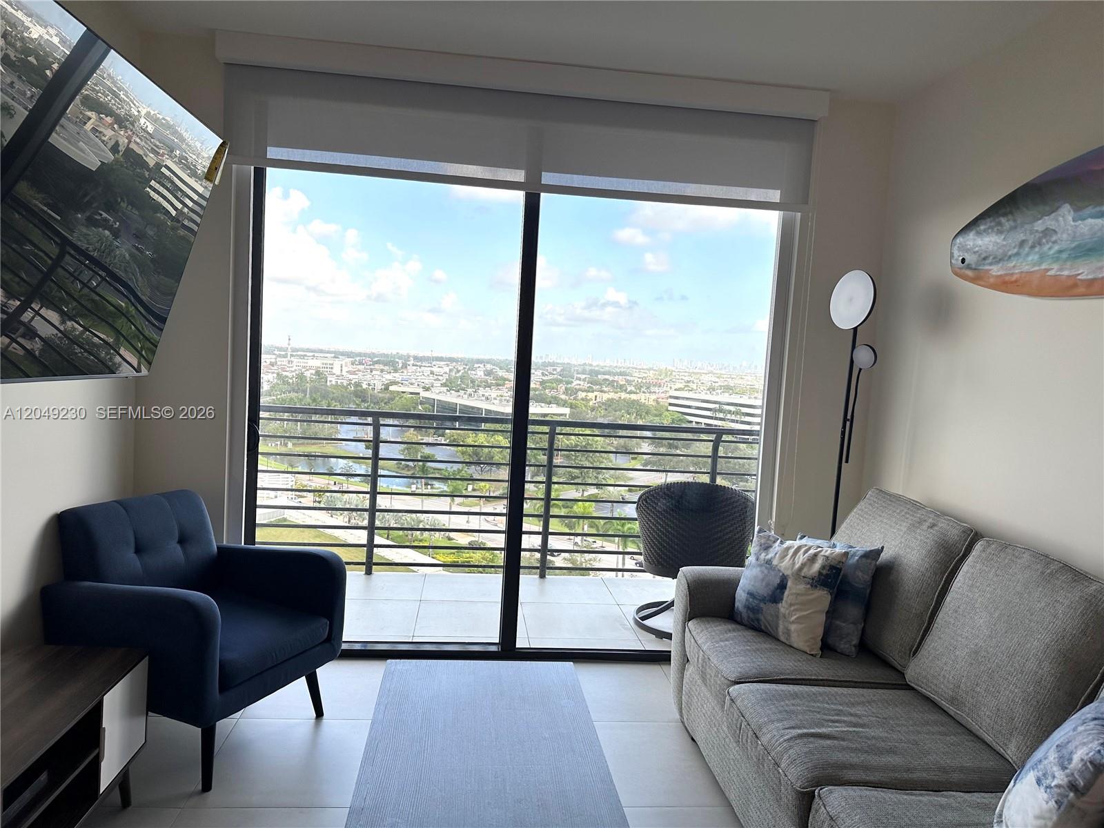 A living room features a blue armchair, gray sofa, and a balcony with city views — 5350 NW 84th Ave # 1107, Doral FL 33166, DORAL, FL