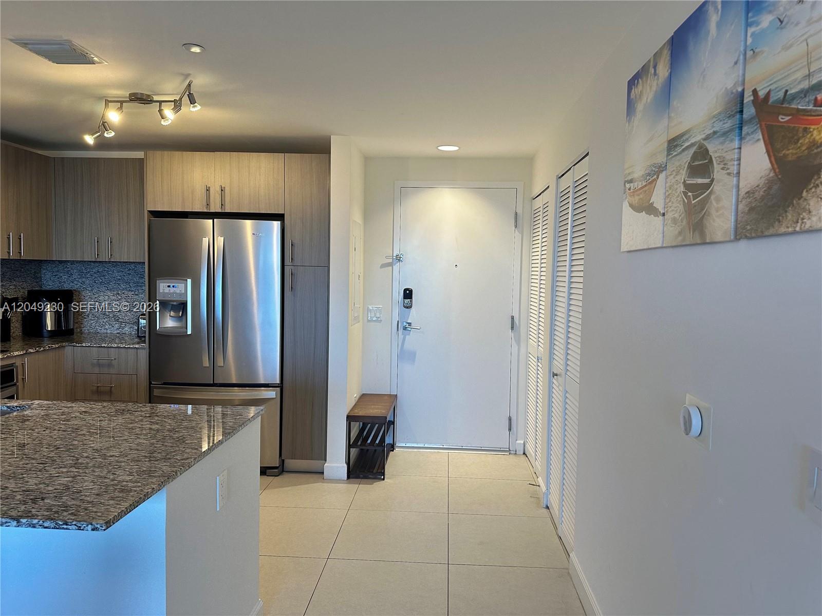 A kitchen with stainless steel appliances and granite countertops opens into an entryway with tile — 5350 NW 84th Ave # 1107, Doral FL 33166, DORAL, FL