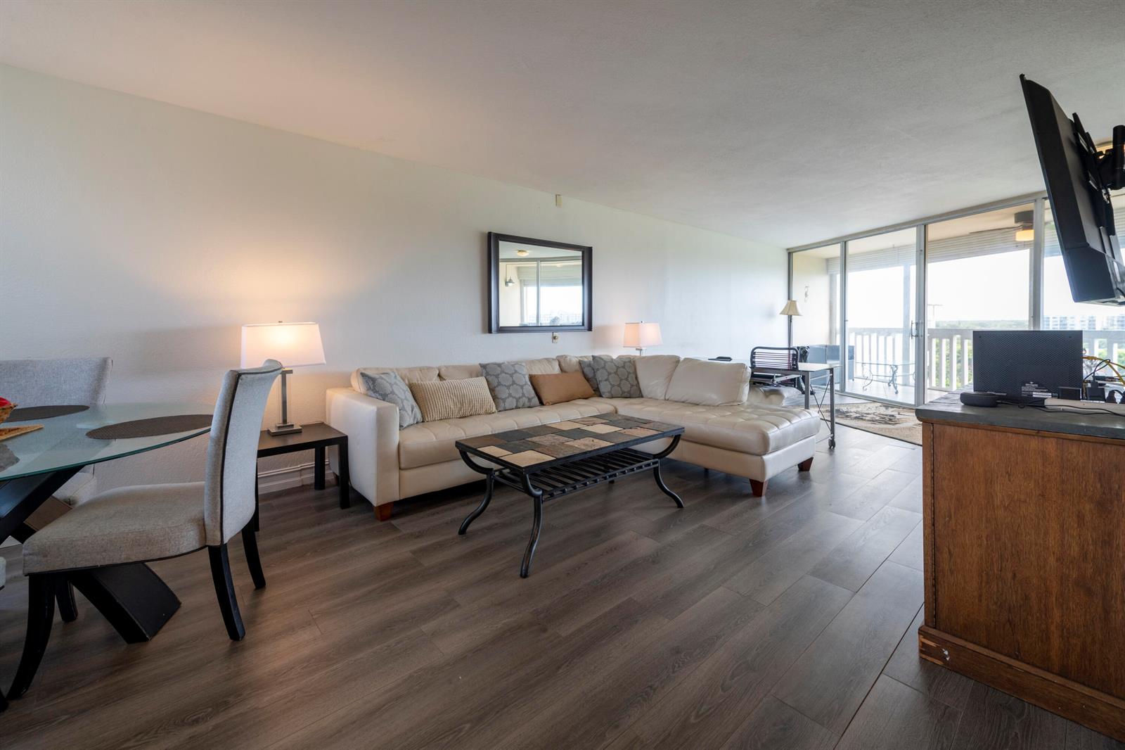 A living room features a white sectional sofa, a tiled coffee table, and wood-look flooring — 6911 Environ Boulevard # 8g, Lauderhill FL 33319, LAUDERHILL, FL