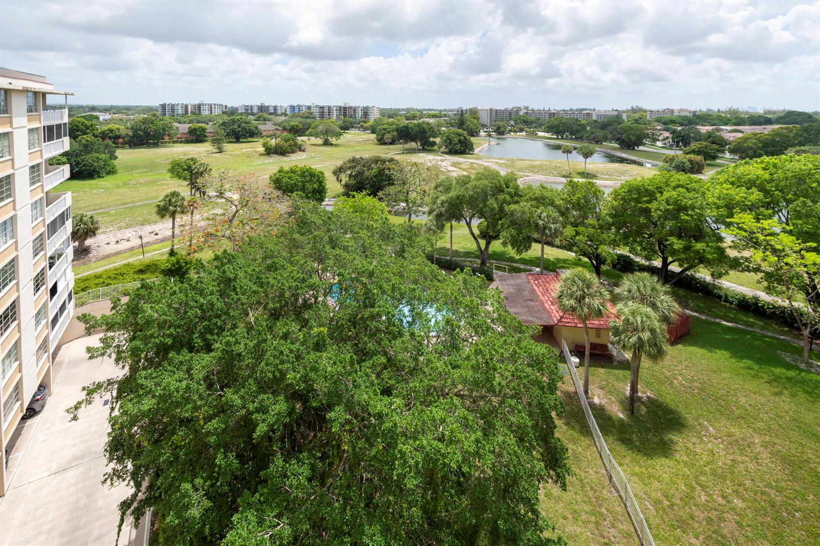 An elevated view shows a residential building next to a pool, trees, and a pond — 6911 Environ Boulevard # 8g, Lauderhill FL 33319, LAUDERHILL, FL