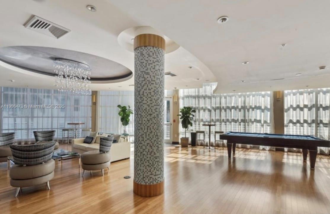 A spacious lounge area features hardwood floors, a mosaic-tiled column, a pool table, and seating — 253 NE 2nd St # 632, Miami FL 33132, MIAMI, FL