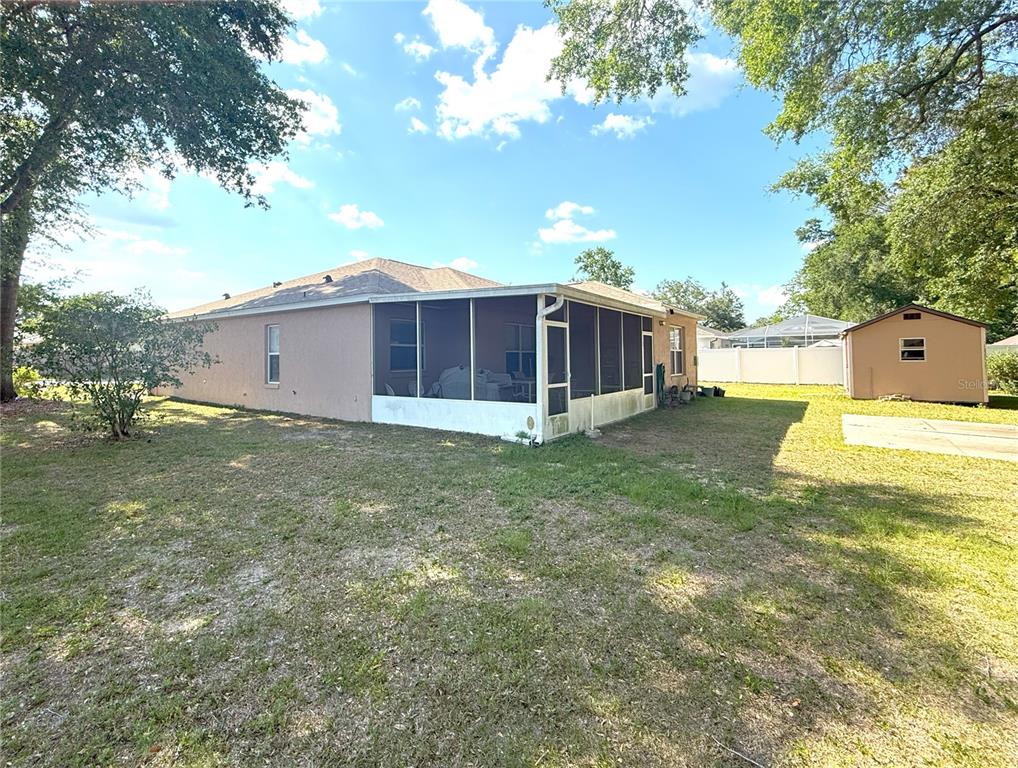 The exterior of a house features a screened-in back porch and a detached storage shed — 1001 NE 22ND AVENUE, OCALA, FL