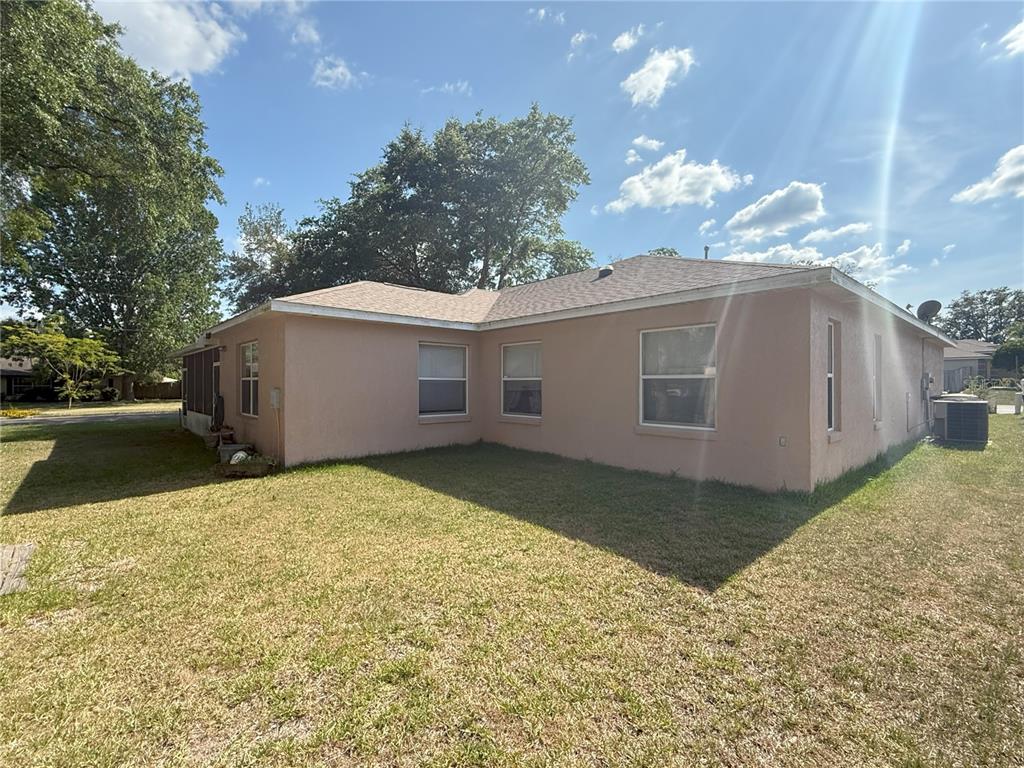 A view of the side and rear exterior of a single-story peach-colored stucco house — 1001 NE 22ND AVENUE, OCALA, FL
