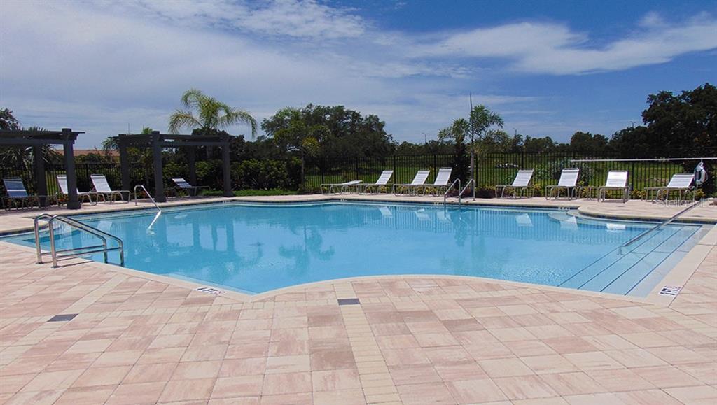 An outdoor swimming pool with lounge chairs and a pergola on a paved deck — 8920 MILESTONE DRIVE, SARASOTA, FL