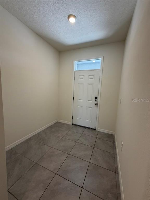 An entryway with light-colored walls, a white door, and gray tiled flooring — 8920 MILESTONE DRIVE, SARASOTA, FL