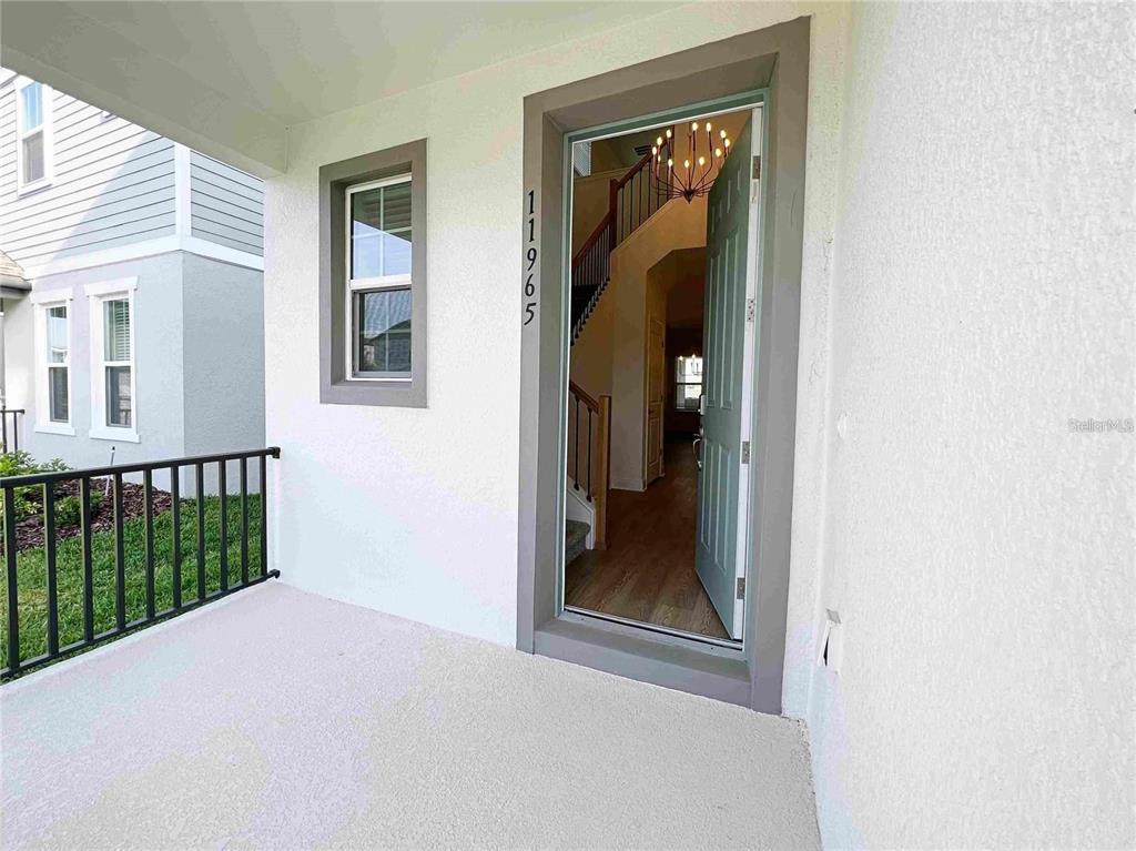 A view of a home's front porch and open front door revealing an interior entryway — 11965 BRACCO STREET, WINTER GARDEN, FL