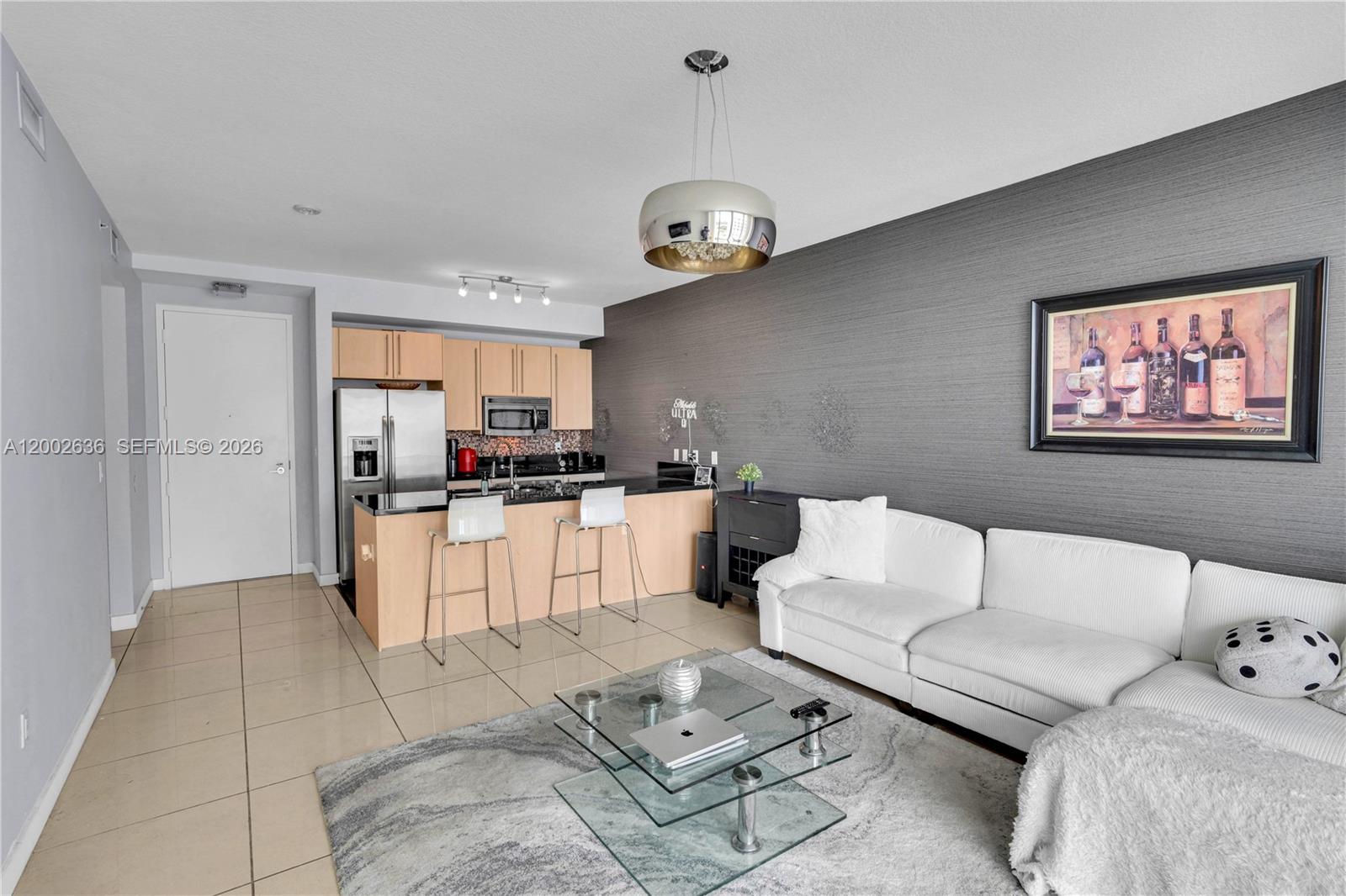 This open-concept living room features a kitchen with light wood cabinets and a white sofa — 79 SW 12th St # 1605, Miami FL 33130, MIAMI, FL