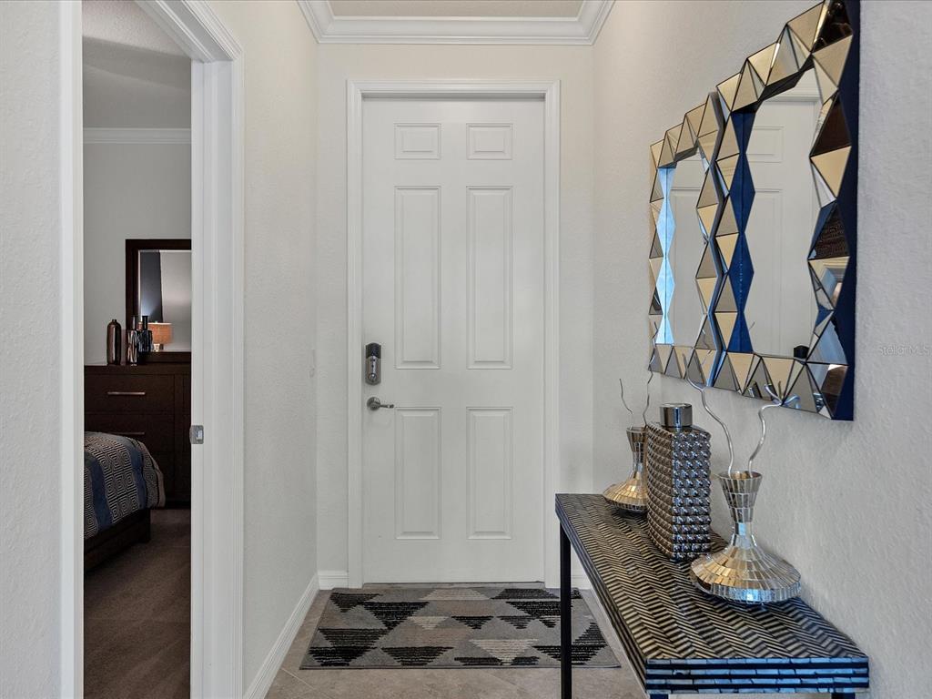 A white door stands at the end of a hallway with a mirrored console table — 16804 VARDON TERRACE UNIT 306, BRADENTON, FL