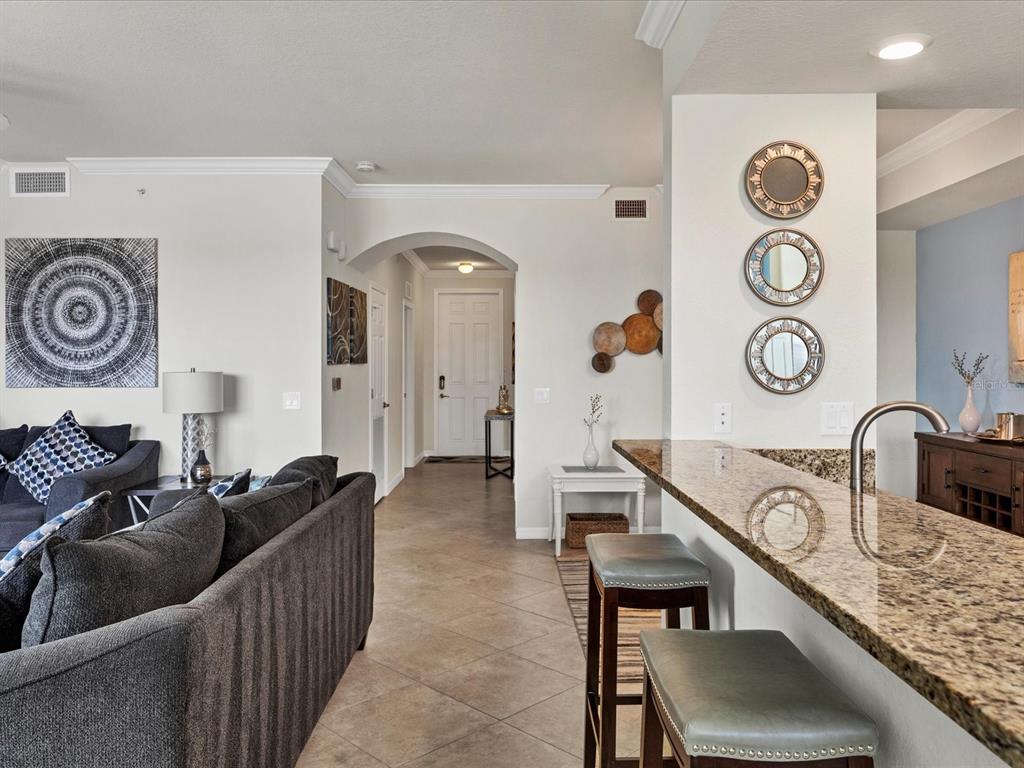 A living room with a gray sofa and a kitchen breakfast bar with granite countertops — 16804 VARDON TERRACE UNIT 306, BRADENTON, FL