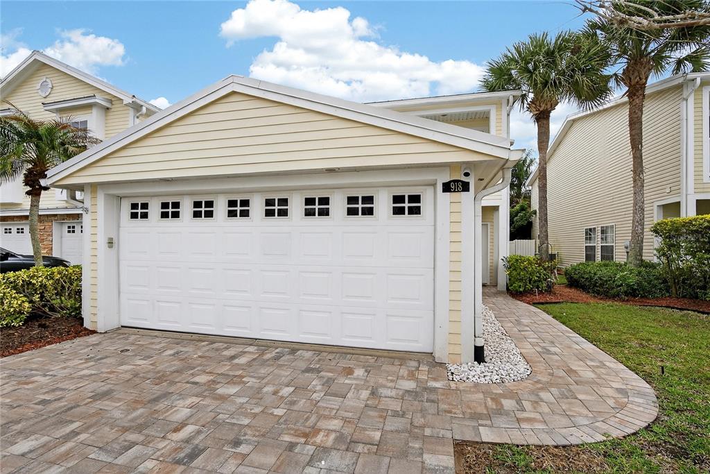 A light yellow house exterior features a white garage door and a paved walkway — 918 WOODBRIDGE COURT, SAFETY HARBOR, FL