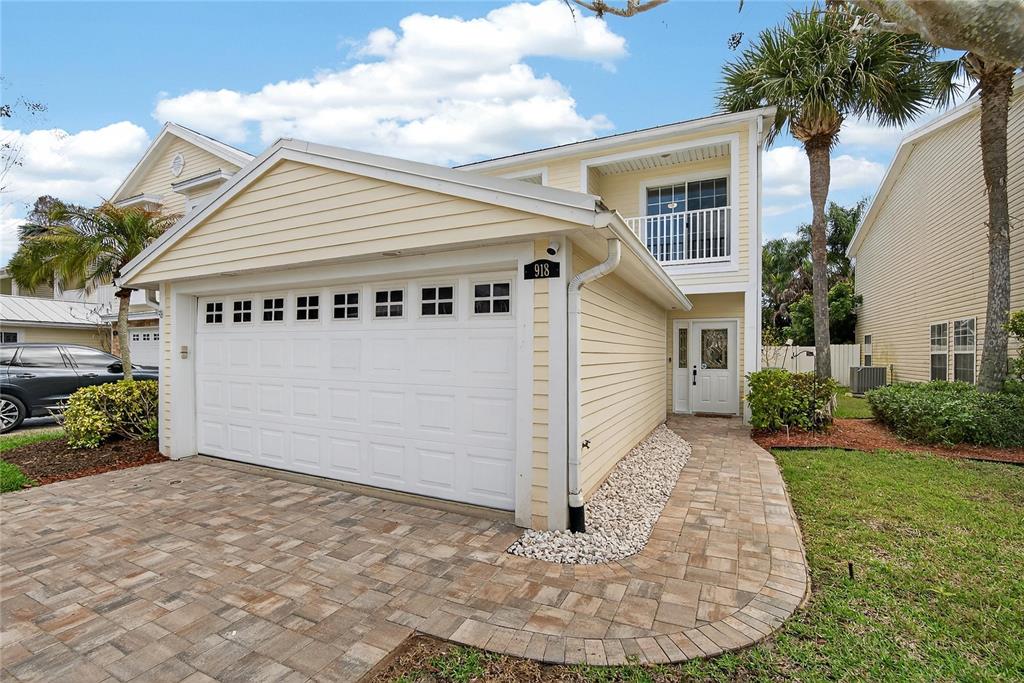 A two-story yellow house with a white garage door and a paved walkway — 918 WOODBRIDGE COURT, SAFETY HARBOR, FL
