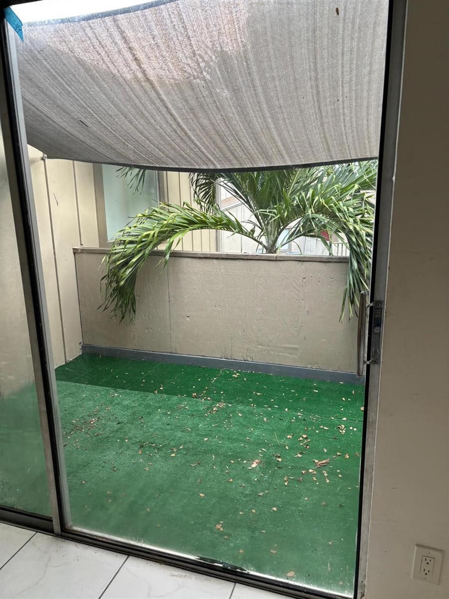 A view through a sliding glass door of a small patio with artificial turf — 2148 NW 57th Avenue # e, Lauderhill FL 33313, LAUDERHILL, FL