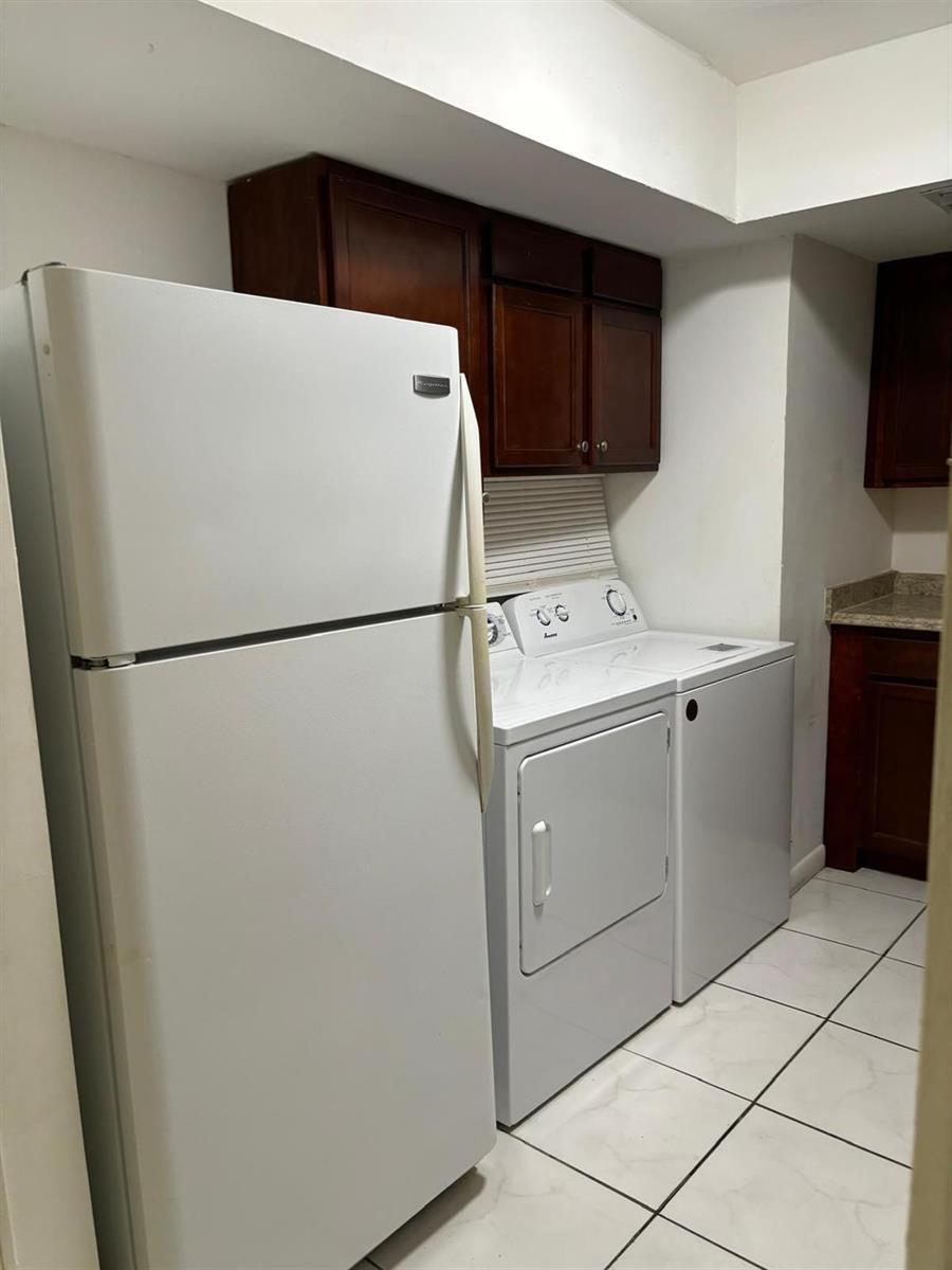 A laundry area features a white refrigerator, a washer, a dryer, and dark wood cabinets — 2148 NW 57th Avenue # e, Lauderhill FL 33313, LAUDERHILL, FL