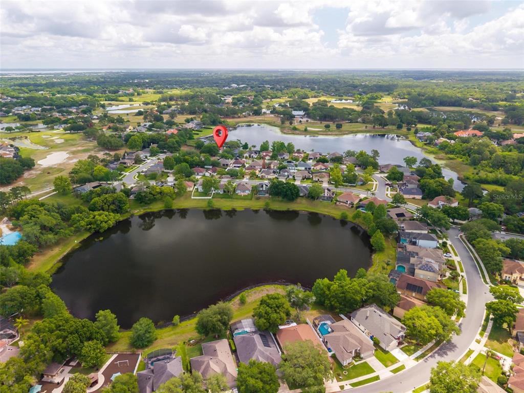 An aerial view shows a residential neighborhood surrounding a large lake under a cloudy sky — 873 PICKFAIR TERRACE, LAKE MARY, FL