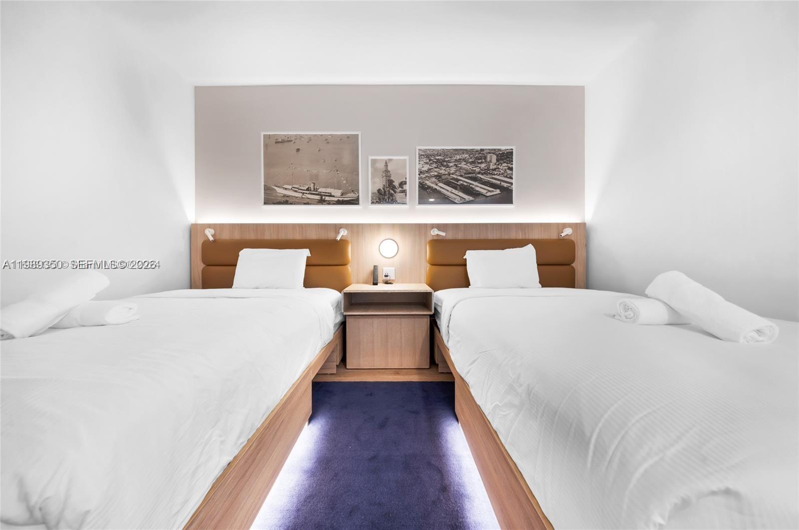 A bedroom features two twin beds with white linens, a central nightstand, and wall art — 159 NE 6 ST # 1617, Miami FL 33132, MIAMI, FL