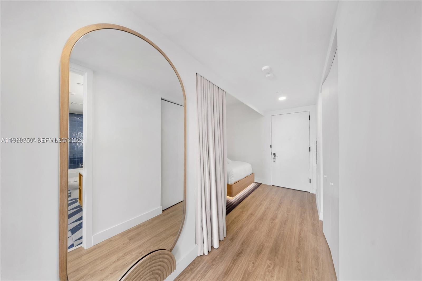 A hallway features light wood flooring, a large arched mirror, and a curtained bedroom area — 159 NE 6 ST # 1617, Miami FL 33132, MIAMI, FL