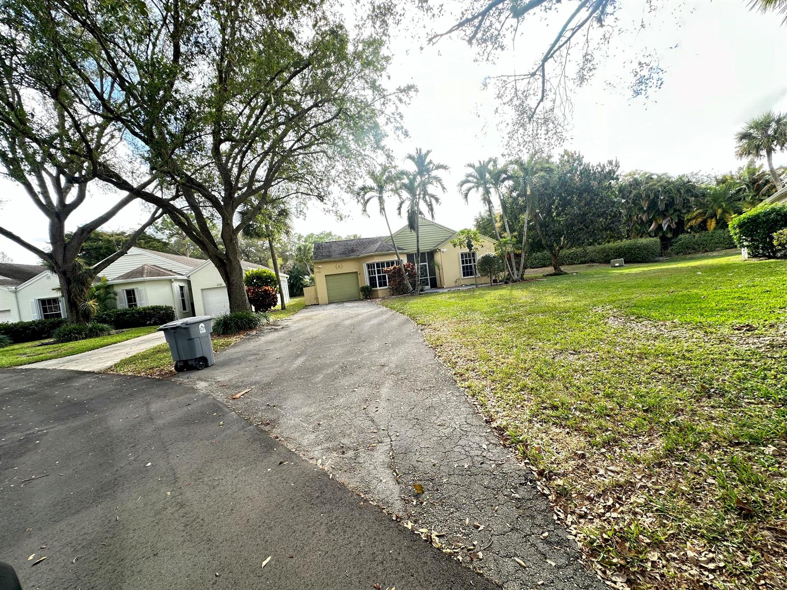 A single-story house with a driveway, a large lawn, and mature trees in the yard — 7729 Forest Green Lane, Boynton Beach FL 33436, BOYNTON BEACH, FL