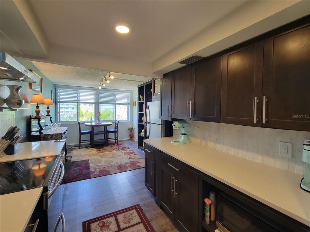 A kitchen with dark wood cabinets and light countertops opens into a dining area — 4720 LOCUST STREET NE UNIT 219, ST PETERSBURG, FL