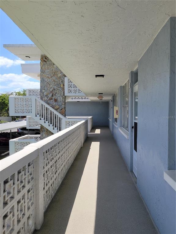 An outdoor walkway with a decorative concrete railing, stone pillar, and stairs at a building — 4720 LOCUST STREET NE UNIT 219, ST PETERSBURG, FL