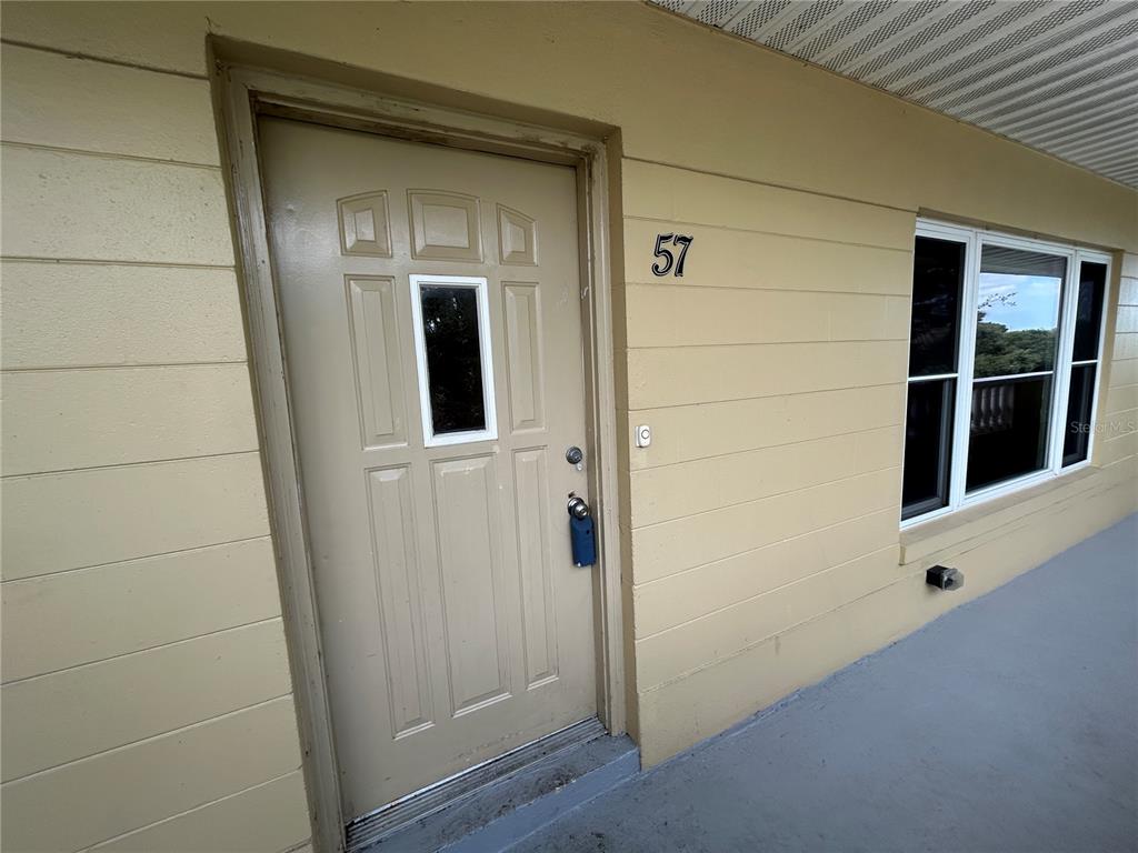 A light yellow exterior wall features a front door with a window and number 57 — 2221 NORWEGIAN DRIVE UNIT 57, CLEARWATER, FL