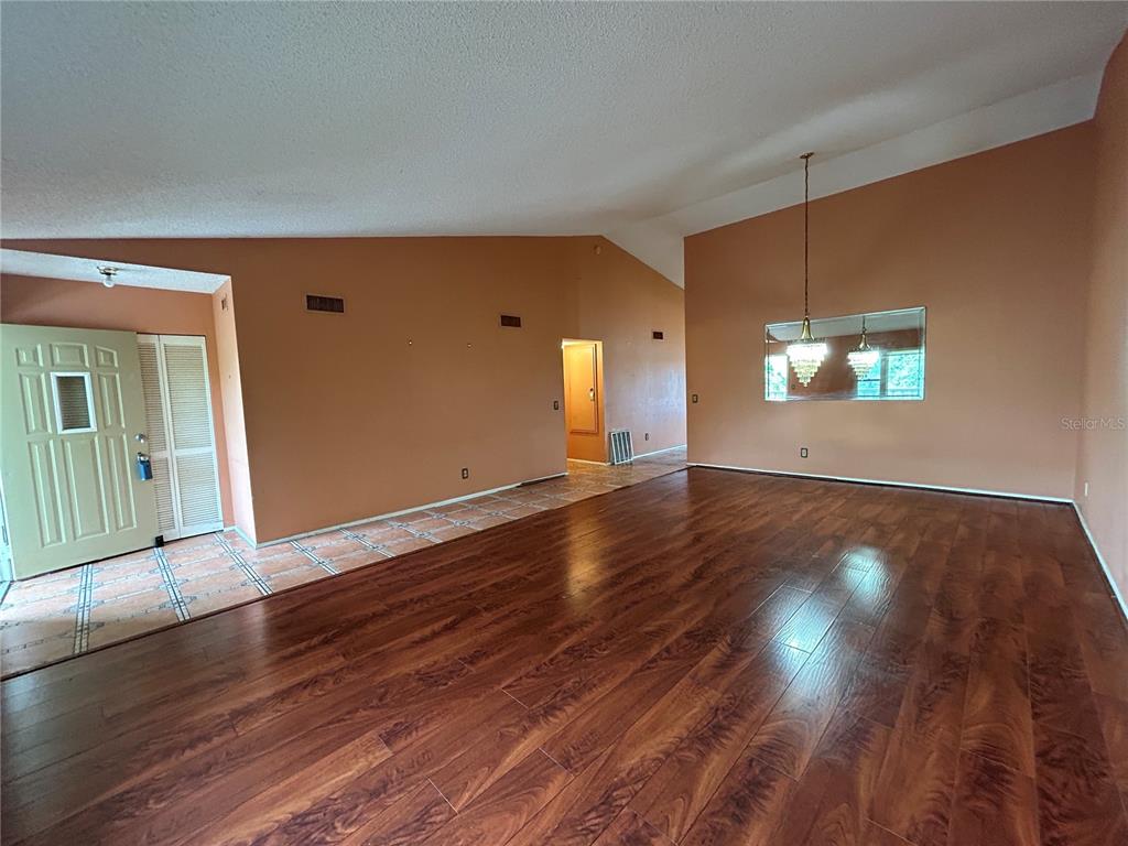 A living room with vaulted ceilings, orange walls, and dark wood-look laminate flooring — 2221 NORWEGIAN DRIVE UNIT 57, CLEARWATER, FL
