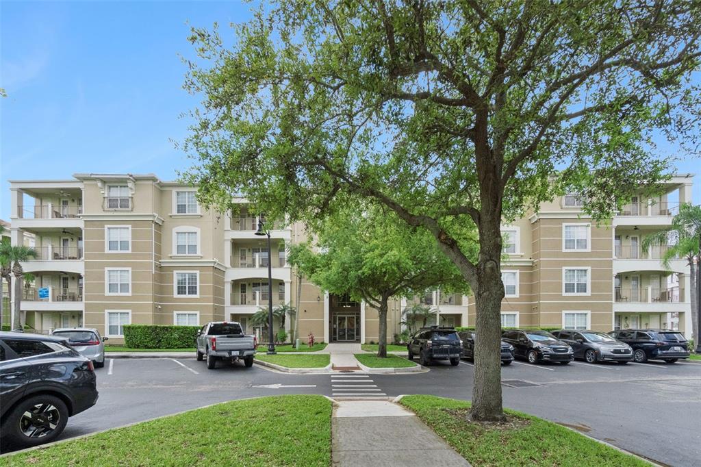 A multi-story apartment building with a parking lot and a tree-lined walkway in front — 4816 CAYVIEW AVENUE UNIT 201, ORLANDO, FL