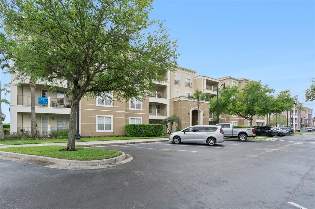 A multi-story apartment building with a parking lot and trees in the foreground — 4816 CAYVIEW AVENUE UNIT 201, ORLANDO, FL