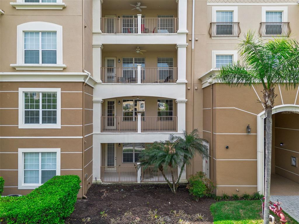 A multi-story apartment building exterior features stacked balconies and tan stucco walls with white trim — 4816 CAYVIEW AVENUE UNIT 201, ORLANDO, FL
