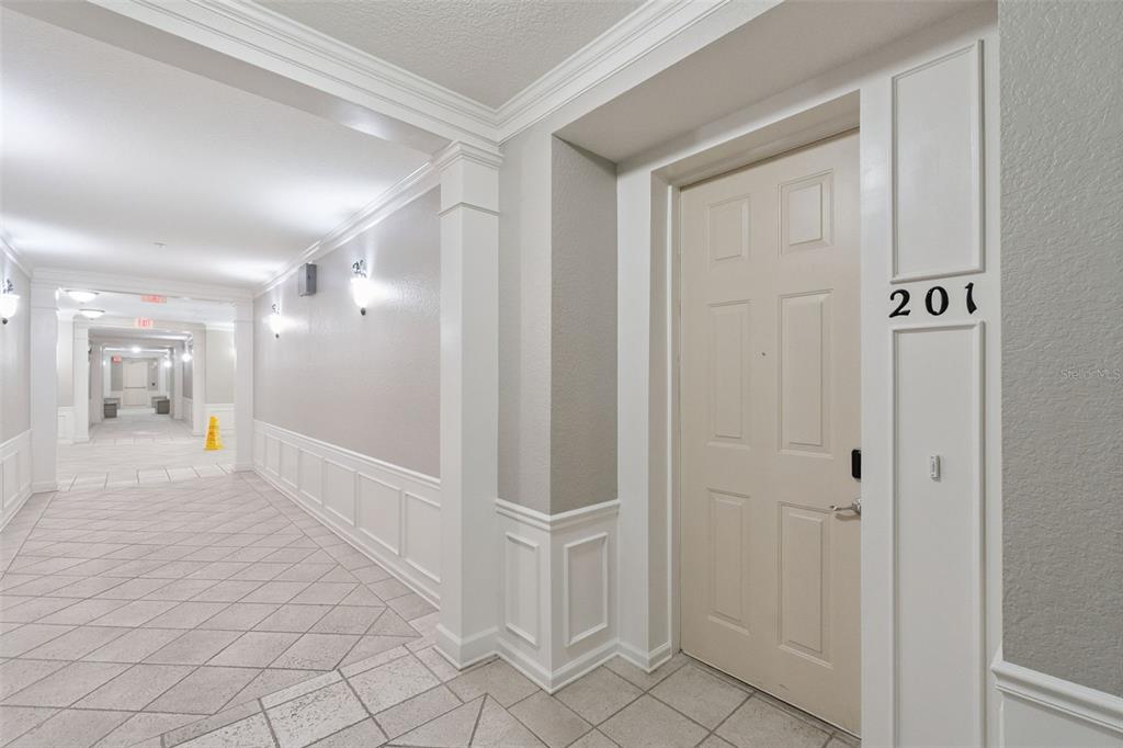 A beige apartment door labeled 201 sits in a brightly lit, tiled indoor hallway — 4816 CAYVIEW AVENUE UNIT 201, ORLANDO, FL
