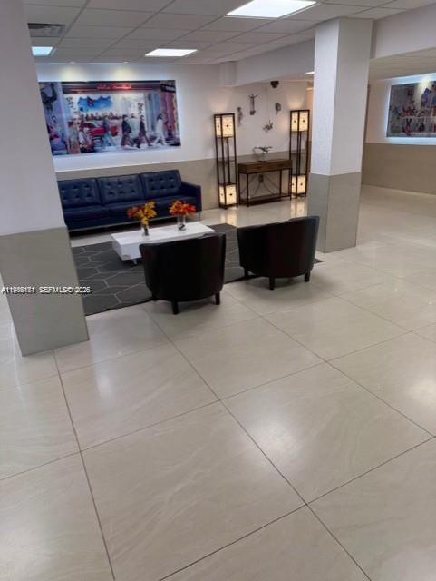A modern lobby features a blue sofa, two dark armchairs, and a white coffee table — 4164 Inverrary Dr # 913, Lauderhill FL 33319, LAUDERHILL, FL