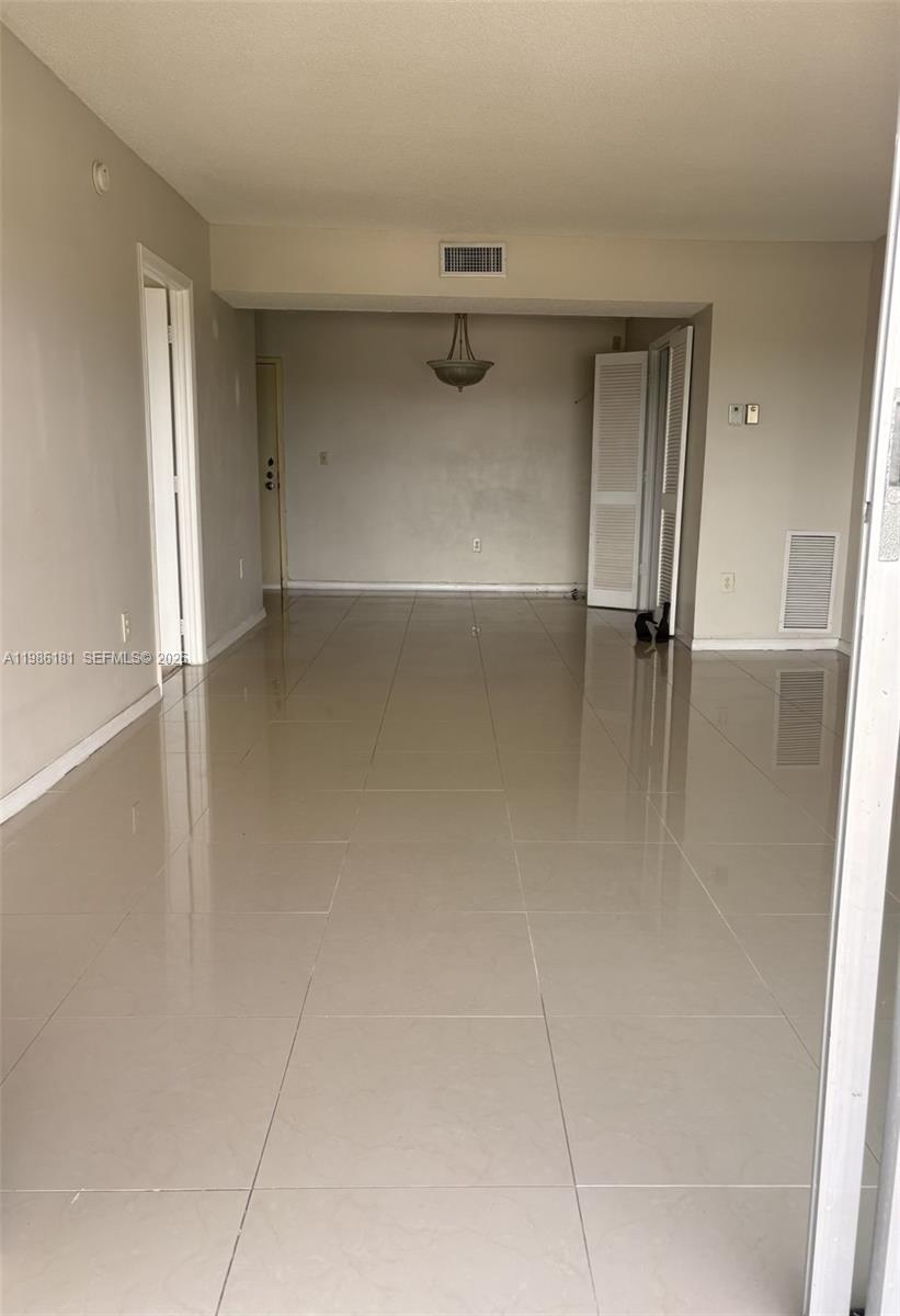 An empty room with light-colored tile flooring, a ceiling light fixture, and white walls — 4164 Inverrary Dr # 913, Lauderhill FL 33319, LAUDERHILL, FL