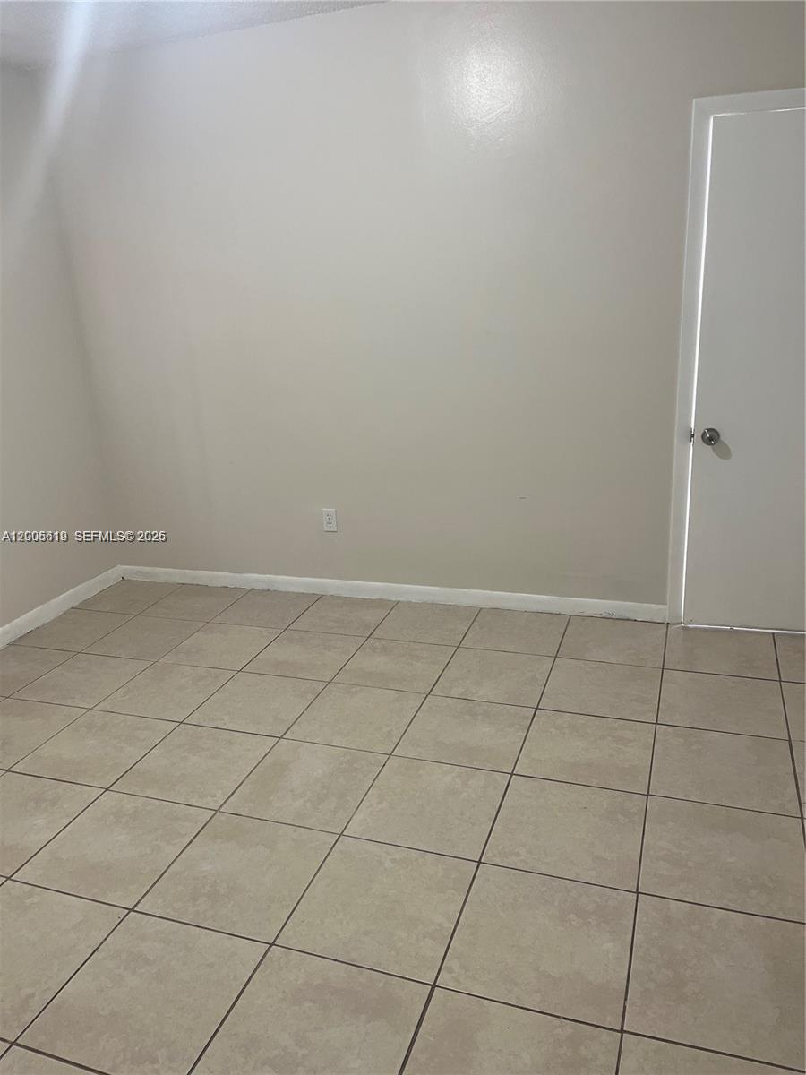 This room features light-colored walls, a white door, and beige square floor tiles — 2255 W 55th St # 2, Hialeah FL 33016, HIALEAH, FL