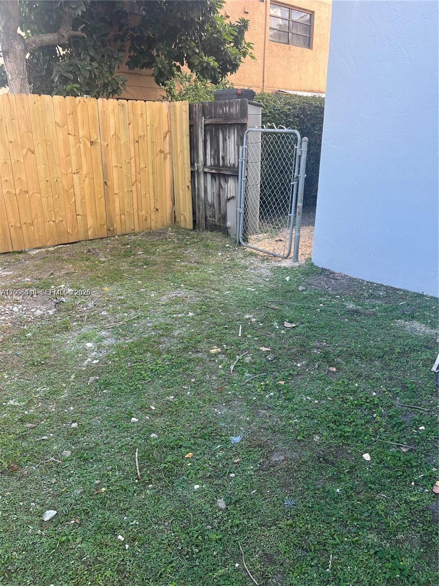 A patch of patchy grass and dirt sits beside a wooden fence and chain-link gate — 2255 W 55th St # 2, Hialeah FL 33016, HIALEAH, FL