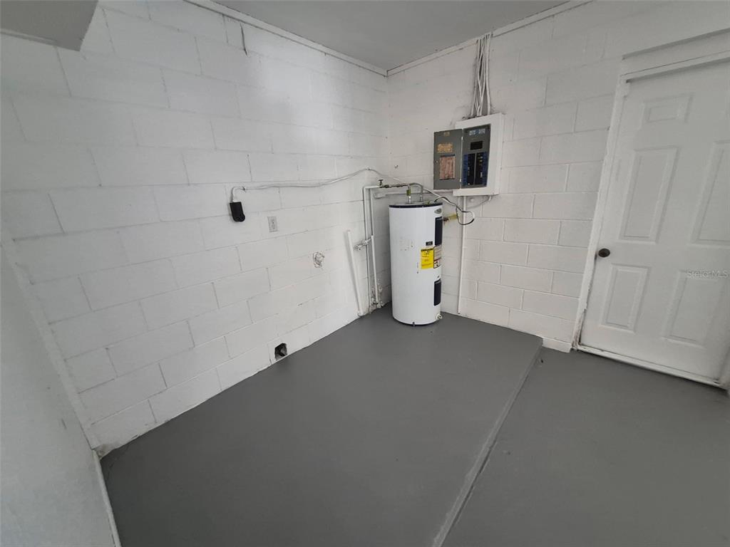 A utility room with a water heater, electrical panel, and white concrete block walls — 5451 NW 3RD PLACE, OCALA, FL