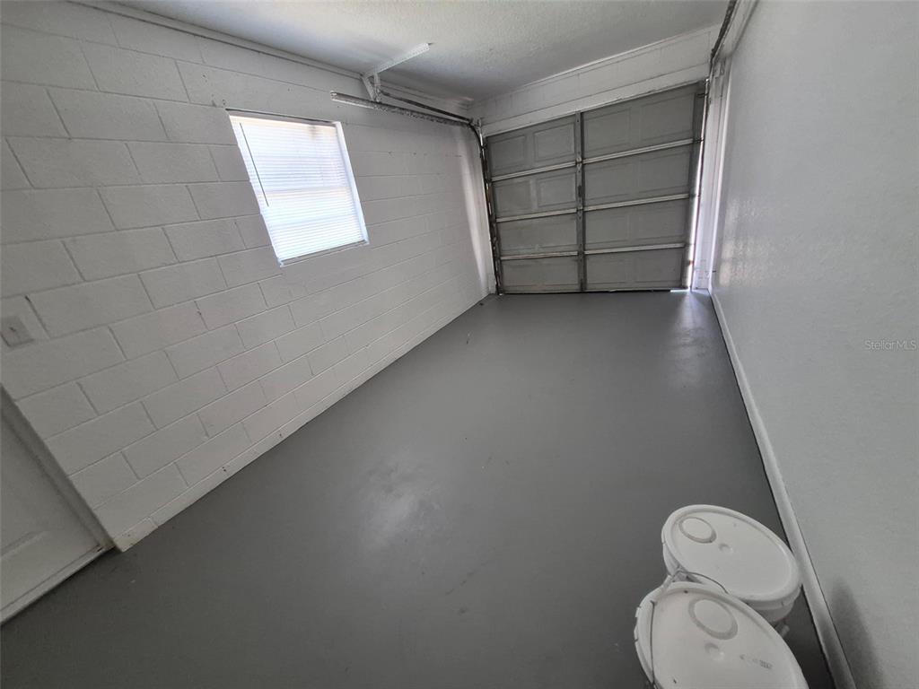 A garage with painted concrete floors, white block walls, a window, and a sectional door — 5451 NW 3RD PLACE, OCALA, FL